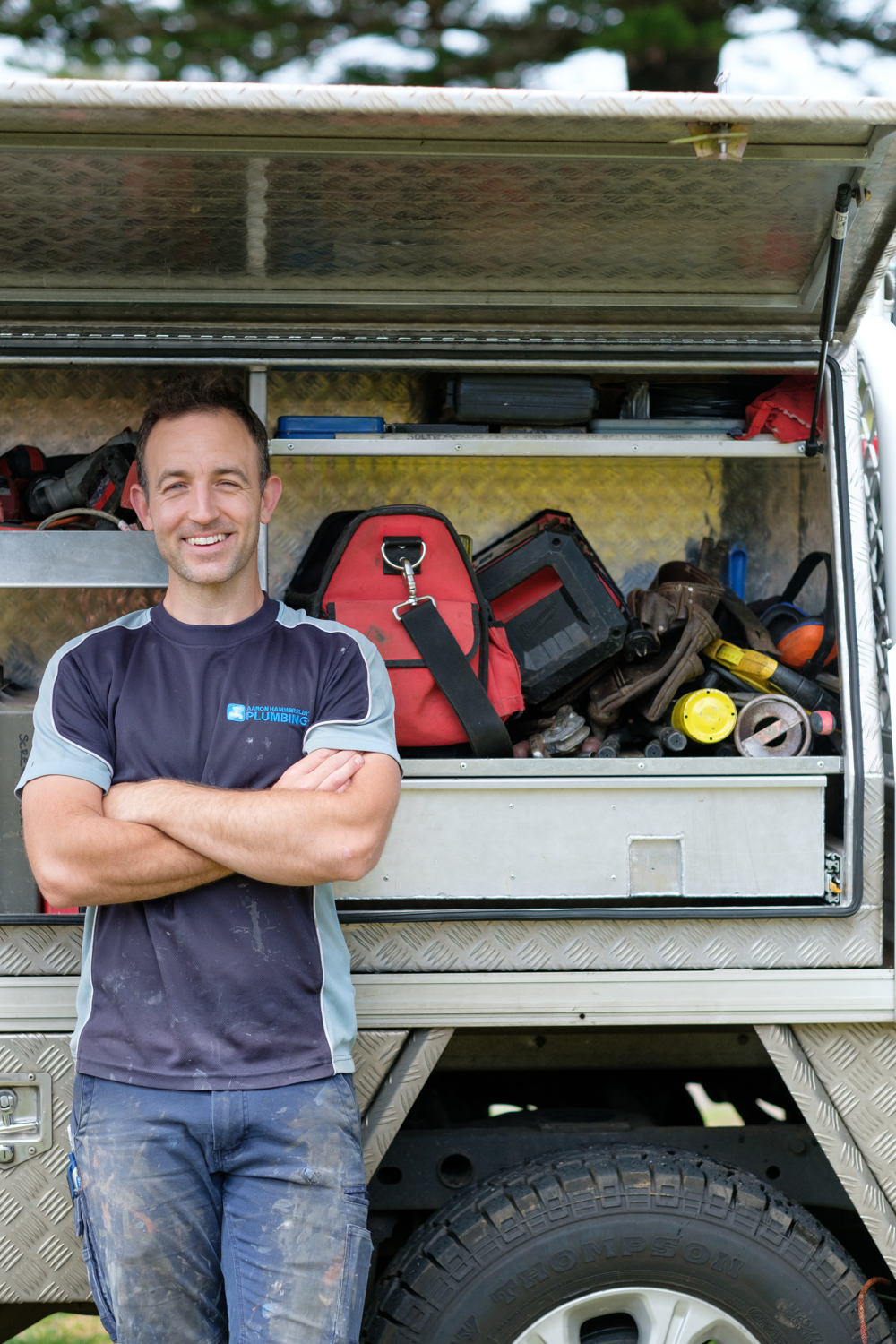 Aaron standing with his plumbing tools and van