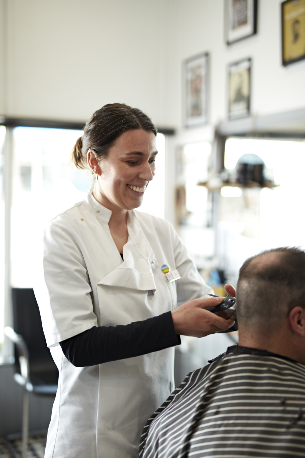 Liz working as a barber, trimming a man's hair