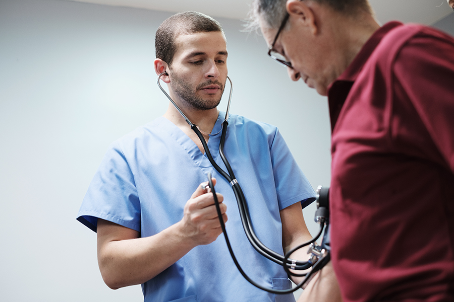 Nurse and Doctor in a Clinic Measure an Hispanic Old Man Blood Pressure. An elderly patient with high blood pressure goes to hospital for medical examination. People and preventing heart disease.